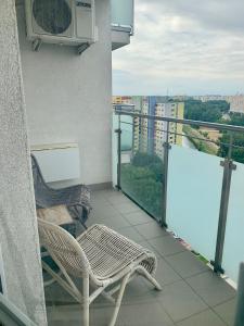 a balcony with two chairs and a air conditioner at Cozy, beautiful view - 1 stop by train to old town in Bratislava