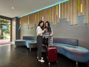 two women standing next to each other with a suitcase at ibis budget Singapore Bugis in Singapore