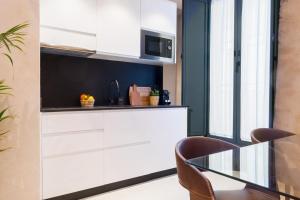 a kitchen with white cabinets and a glass table at Luxurious studio with Jacuzzi in Casa Pilatos in Seville