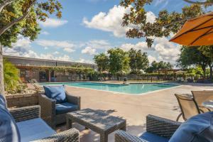 a swimming pool with chairs and an umbrella at Best Western Plus Garden Court Inn in Fremont