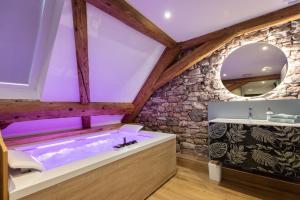 a bathroom with a soaking tub and a stone wall at Lorenz Home - Gîte d exception & balnéo in Neuve-Église +25 photos