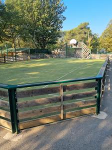 a tennis court with a wooden fence around it at Mobile-Home 6 places Nans les pins in Nans-les-Pins