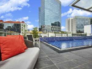 a couch on the roof of a building with a pool at ibis budget Singapore Clarke Quay in Singapore