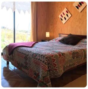 ein Schlafzimmer mit einem Bett mit einer Decke und einem Fenster in der Unterkunft Cabaña en Playa Totoralillo2 in Totoralillo