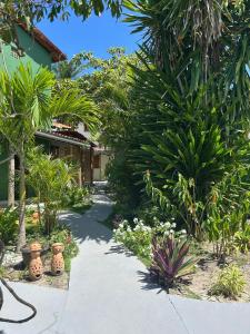 a garden with palm trees and a walkway at Chales Canto dos Pássaros Boipeba in Cayru