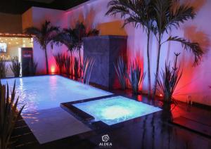 a large swimming pool with palm trees and pink lights at Aldea Express in San Juan Teotihuacán