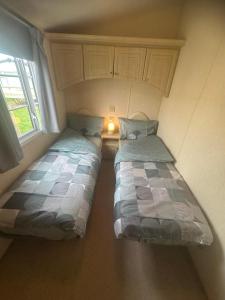 zwei Betten in einem kleinen Zimmer mit Fenster in der Unterkunft Meadow view 93 8 berth Chapel, Skegness SANTANAVAN 15 in Chapel Saint Leonards