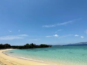 a beach with turquoise water and trees in the distance at GRANDIOSO6-B - Vacation STAY 67693v in Nakama