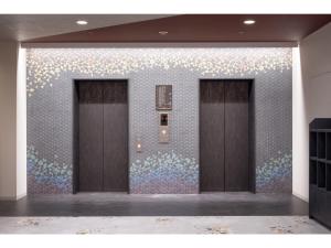 two elevators in a room with a wall of flowers at Smile Hotel Premium Kanazawa Higashiguchi Ekimae - Vacation STAY 65341v in Housai +26 photos