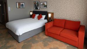 a bedroom with a bed and a red couch at Holiday Inn Bristol City Centre by IHG in Bristol