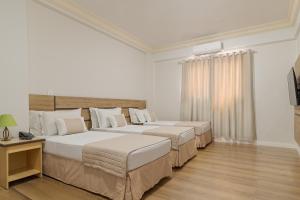 Habitación con 2 camas, paredes blancas y suelo de madera. en Havana Palace Hotel, en Uberaba 54 fotos más