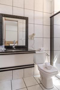 Un baño con inodoro, lavabo y espejo. en Havana Palace Hotel, en Uberaba