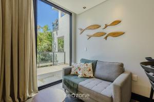 a living room with a chair and a large window at Sua estadia próxima da Praia Brava - BSO in Cabeçudas