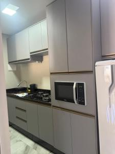 una cucina con mobili bianchi e un forno a microonde di Residencial DX a Guarapuava