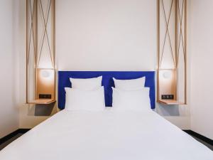 a bed with a blue headboard and two pillows at Mercure Brest Centre Port in Brest +43 photos