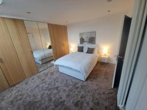 エディンバラにあるEdinburgh West Luxury 5 Bedroom Homeの白いベッドと鏡のある寝室