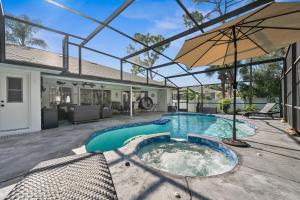 a swimming pool with an umbrella and a house at Sunset Sands Retreat in Venice