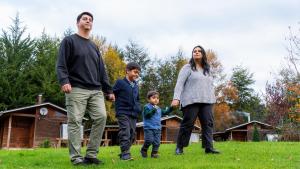 Una familia caminando por el césped de un patio. en Turismo Jaos Cabañas Tinas y Quincho, en Futrono