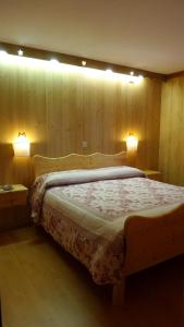 Un dormitorio con una cama de madera con dos luces. en Albergo Ristorante K2, en Roana