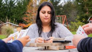 富特罗诺Turismo Jaos Cabañas Tinas y Quincho的一位女士坐在桌旁，和两个人一起玩牌。 更多128张照片