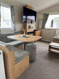 un salon avec une table et un canapé dans l'établissement Seaside Charm Cabin Retreat in Rhyl, à Rhyl