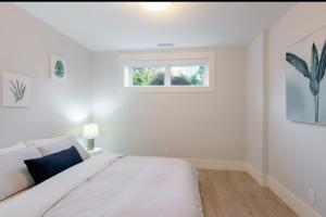 伯纳比2BR Suite Close to Transit - Great for FIFA Vancouver的一间带床和窗户的白色卧室