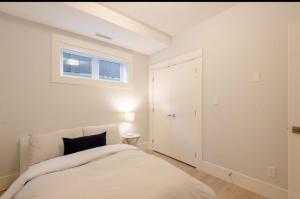 伯纳比2BR Suite Close to Transit - Great for FIFA Vancouver的一间带床和窗户的白色卧室