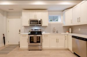 伯纳比2BR Suite Close to Transit - Great for FIFA Vancouver的厨房配有白色橱柜、炉灶和微波炉。