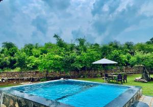 a swimming pool with a table and an umbrella at Sayar Bagh Jawai in Nāna