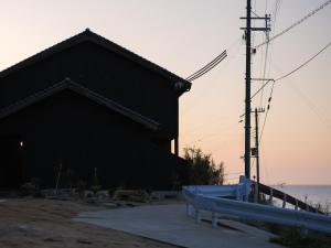 a black building with a bench next to the ocean at umieru - Vacation STAY 50097v in Taiza