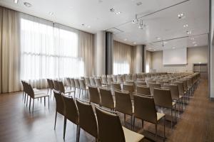 una sala de conferencias con sillas, un podio y una pantalla en NH Parma, en Parma