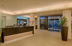 an office lobby with a reception desk and plants at NH Linate in Peschiera Borromeo