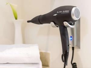 a black blow dryer on a table next to a bed at NH Linate in Peschiera Borromeo