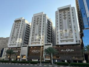 two tall buildings with palm trees in front of a street at دار المشاعر in Mecca