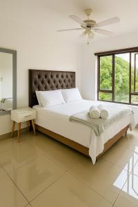 a bedroom with a large bed with a ceiling fan at Tranquil Shores Modern 1BR WiFi Pool Beach in Richards Bay