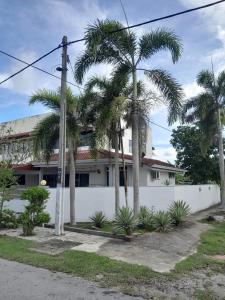 a white building with palm trees in front of it at RUMAH BENDANG ALOQSETAQ -Private PooL - Panoramic view of rice fields and Alor Setar Tower in Alor Setar