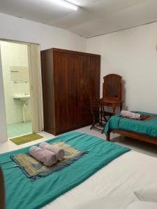 a bedroom with two beds and a table and a chair at RUMAH BENDANG ALOQSETAQ -Private PooL - Panoramic view of rice fields and Alor Setar Tower in Alor Setar +13 photos