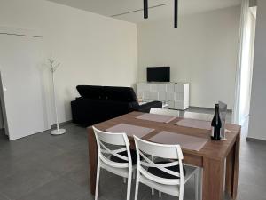 a dining room table with two white chairs and a bottle of wine at B&B Bozzini's Nest in Bagnolo San Vito