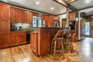 eine Küche mit Holzschränken und eine Bar mit Hockern in der Unterkunft Cedar Crest - Owl Cottage 9 in Homewood