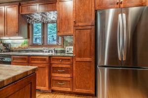 eine Küche mit Holzschränken und einem Edelstahlkühlschrank in der Unterkunft Cedar Crest - Owl Cottage 9 in Homewood + 40 Fotos