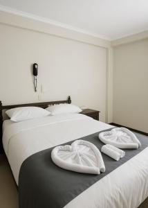 2 camas con toallas blancas encima en Hotel Naciones Unidas, en Lima