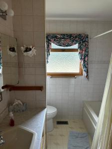 a bathroom with a window and a tub and a toilet at Cozy Farmhouse B&B Retreat in Williams Lake