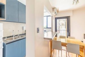 a kitchen with blue cabinets and a wooden table at Moderno departamento en Cañitas in Buenos Aires