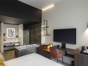 a room with a bed and a television and a tub at Mercure Namur Hotel in Namur +158 photos