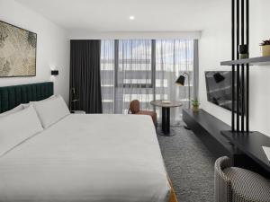 a hotel room with a large white bed and a table at The Sebel Canberra Campbell in Canberra +42 photos