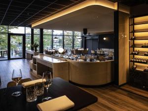 a restaurant with a bar with wine glasses on tables at Mercure Namur Hotel in Namur
