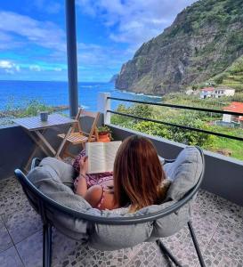 a girl laying in a chair reading a book at Dhamma Guest House in Ponta Delgada