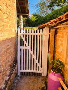 een wit hek met een bloempot naast een gebouw bij Casinha hibisco in Conceição da Ibitipoca