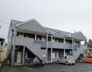 ein Gebäude mit einem auf einem Parkplatz geparkten Auto in der Unterkunft Apartment Primeira Classe Room 1A - Vacation STAY 54531v in Imaichi