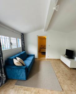 Una sala de estar con un sofá azul y un televisor. en La Cabane du Soleil, en Beausoleil